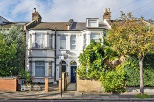 une maison blanche avec un arbre en face dans l'établissement Charming Flat In Shepherds Bush, à Londres