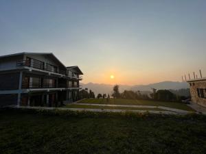 a house with the sunset in the background at The Stone Age : a boutique hotel in Shimla