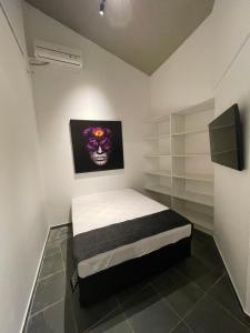 um quarto com uma cama com uma pintura de crânio na parede em Acomodações do Tio Will - 2 no Guarujá