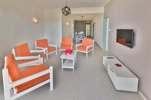 a waiting room with orange chairs and a tv at OceanBreeze Apartments Mont Choisy in Mont Choisy