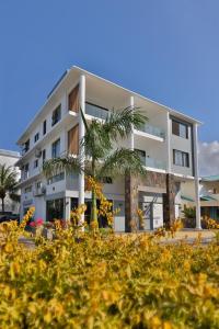 a white building with a palm tree in front of it at OceanBreeze Apartments Mont Choisy in Mont Choisy