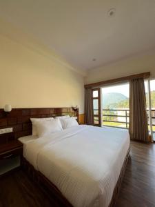 um quarto com uma cama grande e uma janela grande em The Stone Age : a boutique hotel em Shimla