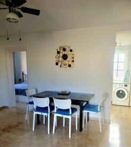 a dining room table with chairs and a clock on the wall at 'Casa Ideal' A22 - Las Arenas Complex in Caleta De Fuste