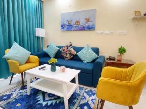 a living room with a blue couch and two chairs at Luxe 2BHK by Coral BnB with Pool access in Dabolim