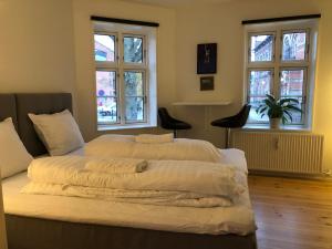 a bedroom with two beds and two windows at Huset ved springvandet in Randers