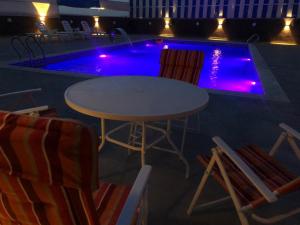 a table and chairs next to a swimming pool at night at Cali Chalet in Al Karāmah