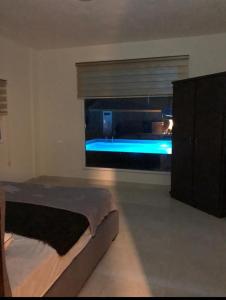 a bedroom with a bed and a window with a tub at Cali Chalet in Al Karāmah