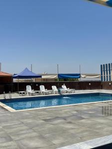 a swimming pool with lounge chairs and a swimming pool at Cali Chalet in Al Karāmah