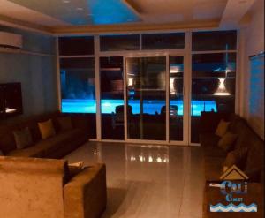 a living room with a couch and a large window at Cali Chalet in Al Karāmah