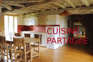 a kitchen with a table and a white refrigerator at Chambres - Gîtes Les FLeuries in Saint-Méen-le-Grand +11 photos