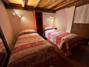 - 2 lits dans une chambre dotée de plafonds en bois dans l'établissement Maison Ricci, à Oulx