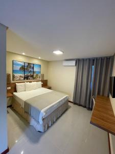 een slaapkamer met een bed, een bureau en een televisie bij Pousada Le Baron in Praia do Frances