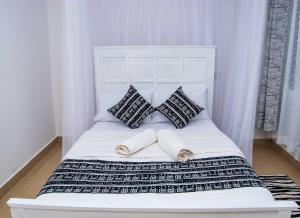 1 cama blanca con 2 almohadas y toallas en Tina's cosy 2br : Wi-fi & Parking in Milimani, en Kisumu