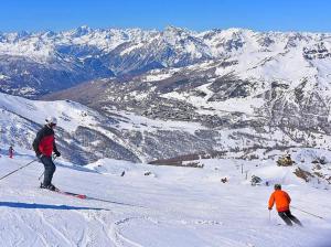 2 personnes sont en train de skier sur une montagne enneigée dans l'établissement Maison Ricci, à Oulx