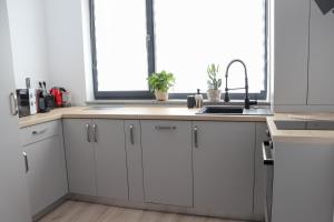 a kitchen with white cabinets and a sink and a window at Ivory Pipera in Voluntari