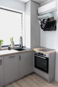 a kitchen with white cabinets and a sink and a stove at Ivory Pipera in Voluntari