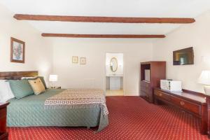 1 dormitorio con 1 cama, vestidor y TV en Blue Spruce Inn & Suites, en Valatie