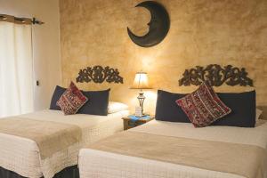 2 camas en una habitación con luna creciente en la pared en Hotel Posada de la Luna, en Antigua Guatemala