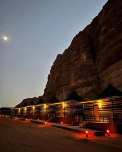 budynek przed górą w nocy w obiekcie SOlARIS WADI RUM CAMP w mieście Wadi Rum