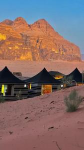 een gebouw in de woestijn met een berg op de achtergrond bij SOlARIS WADI RUM CAMP in Wadi Rum