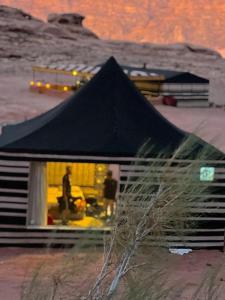 a black tent in front of a house at SOlARIS WADI RUM CAMP in Wadi Rum