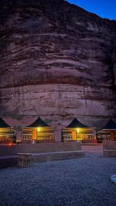 a group of lodges in front of a mountain at night at SOlARIS WADI RUM CAMP in Wadi Rum