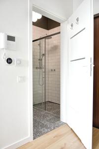 Un baño con ducha con puerta de cristal. en Apartament Heaven Hanza Tower 17th floor, en Szczecin