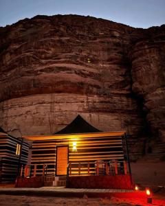 budynek przed górą w nocy w obiekcie SOlARIS WADI RUM CAMP w mieście Wadi Rum