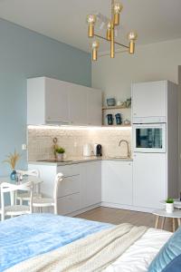Una cocina con gabinetes blancos y una mesa y sillas. en Apartament Heaven Hanza Tower 17th floor, en Szczecin