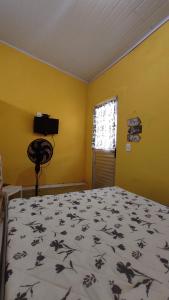 ein Schlafzimmer mit einem Bett und einer gelben Wand in der Unterkunft Quartos simples e aconchegantes na orla de Itaparica in Itaparica Town
