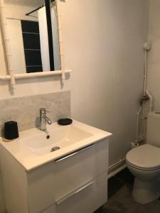 La salle de bains est pourvue d'un lavabo blanc et de toilettes. dans l'établissement Petite maison avec jardin face mer, à Agon-Coutainville