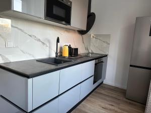 a kitchen with white cabinets and a black counter top at Nana Apartment in Poruba