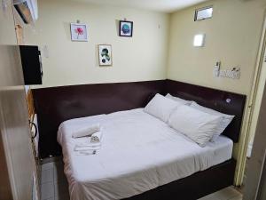 uma cama com lençóis brancos e toalhas em 24Seven Guesthouse em Kuala Lumpur