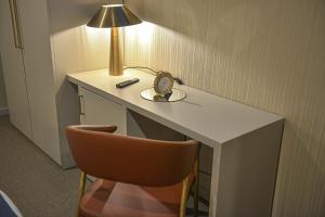 a desk with a lamp and a clock and a chair at Hotel America in Porto