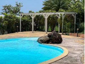 a swimming pool with a rock and a pergola at La Fleur des Caraïbes in Saint-Claude