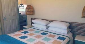 a bedroom with a bed with four pillows on it at Secrets 2 at Waterkant 7 in Jeffreys Bay