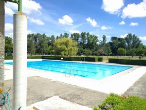 a large swimming pool with blue water and a pole at Studio - Les Traversières in Eymet
