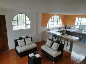 安巴托的住宿－4 Suite Balcón estelar Ambato，客厅配有两把椅子和一张桌子,厨房配有