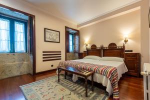 a bedroom with a bed with a bench on it at Hotel - Casa de Turismo Rural Dugium in Finisterre