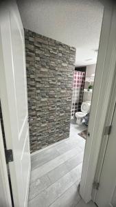 a bathroom with a stone wall and a toilet at Fully Separate & Private Guest Suite in Edmonton