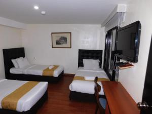 um quarto de hotel com duas camas e uma televisão de ecrã plano em HOTEL MX BOGOTA em Bogotá