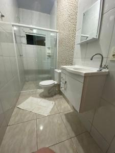 a white bathroom with a toilet and a sink at Casa confortável na terra das cataratas in Foz do Iguaçu