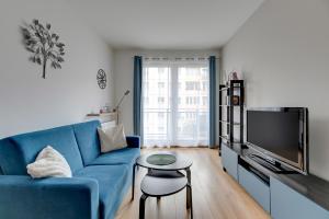 a living room with a blue couch and a tv at Wave Apartments Nowa Grobla Old Town in Gdańsk