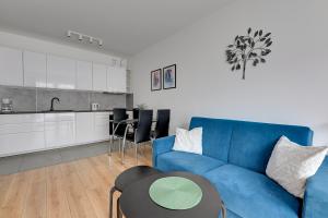 a living room with a blue couch and a kitchen at Wave Apartments Nowa Grobla Old Town in Gdańsk
