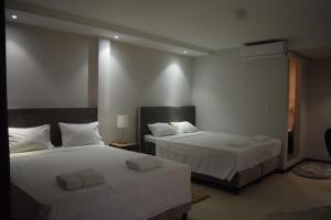 um quarto com 2 camas e lençóis brancos em Hotel RITZZ em Paramaribo