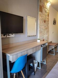 a desk with a television on a wall with a blue chair at ANASTASIA ELENI in Kallithea Halkidikis