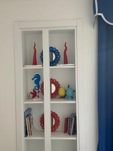 a white book shelf with red and blue dishes on it at Appartamento vista mare Aria 'e mare tra Pompei e Sorrento in Castellammare di Stabia