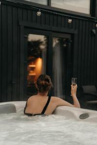 Villa Lakstīgalas في Skrīveri: امرأة في حوض الاستحمام عقد كوب من النبيذ