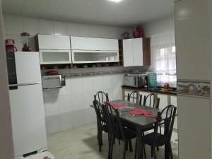 eine Küche mit einem Tisch mit Stühlen und einem Kühlschrank in der Unterkunft Casa Ampla e Confortável a 10 minutos Praia Ubatumirim Cambuca in Ubatuba + 21 Fotos