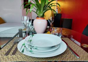 a table with plates and glasses and a potted plant at L'Art de la Sérénité - Prime Host - Calme & Confort in LʼHay-les-Roses